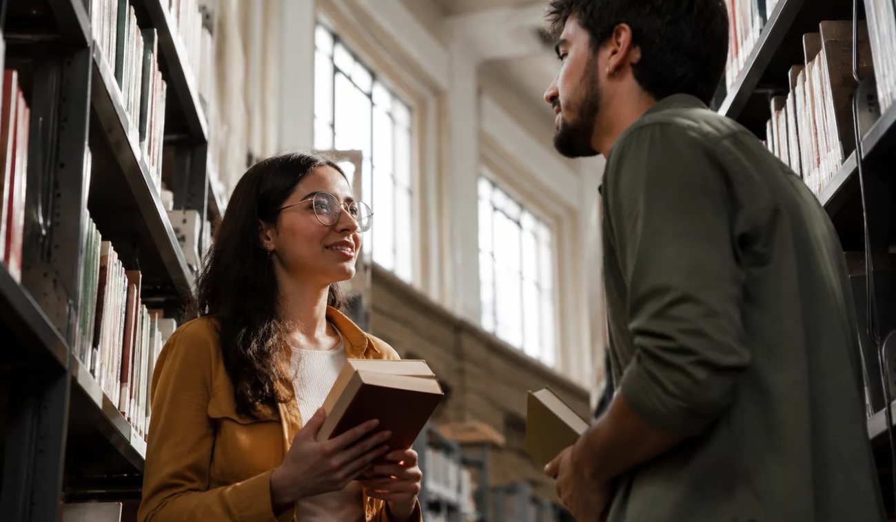 Pessoas conversando de pé junto às estantes antes de o encontro abrir
